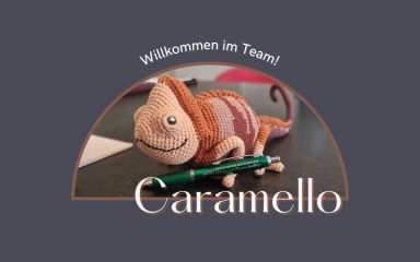 Gehäkeltes Chamäleon Caramello auf Tisch mit Stift, Schriftzug Willkommen im Team.