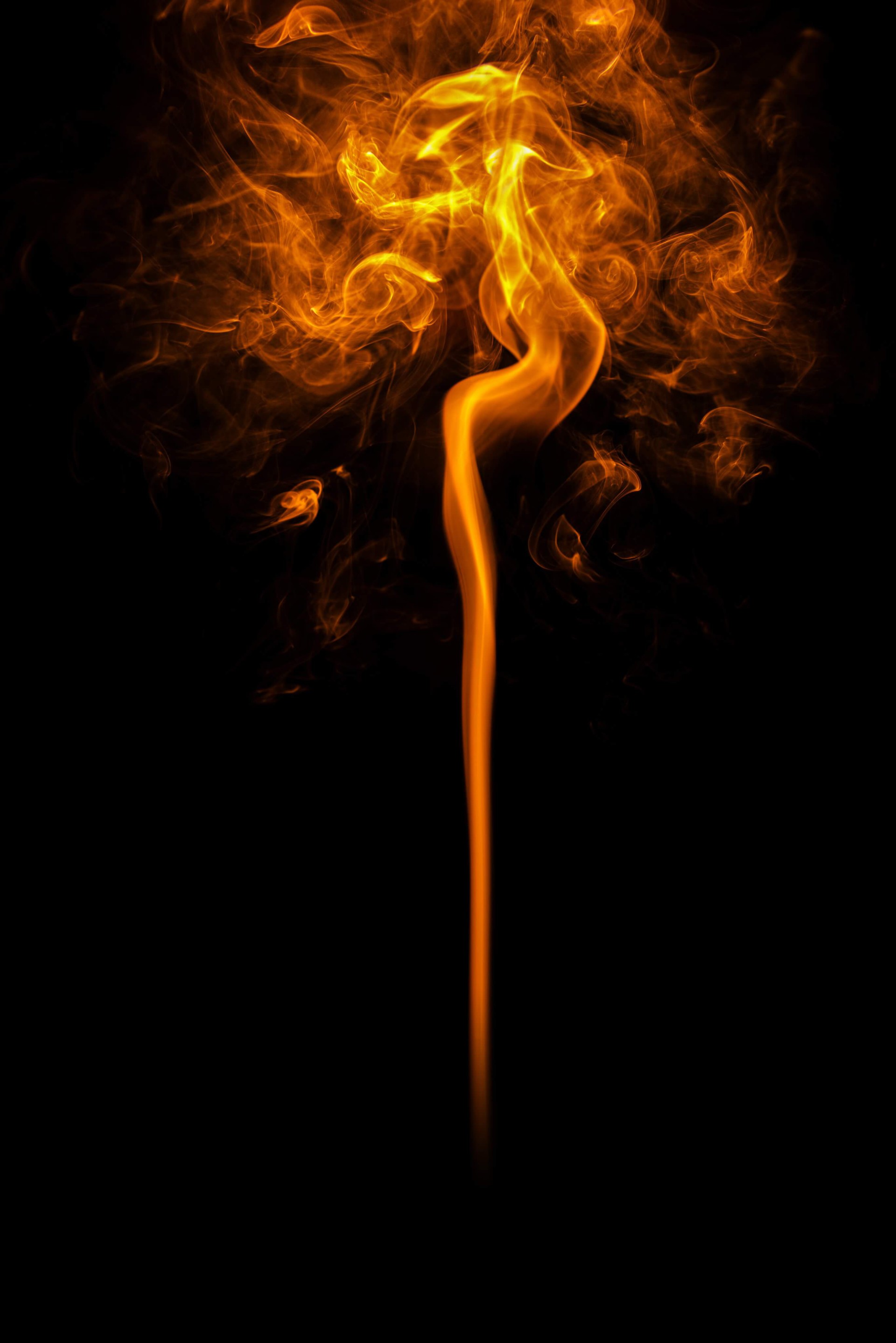 Leuchtend orange Flamme mit wirbelnden Rauchschwaden vor tiefschwarzem Hintergrund.