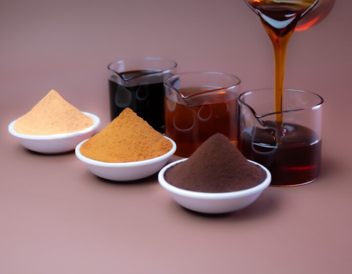 Drei Schalen mit braunen Pulvern vor Bechern dunkler Flüssigkeit, Sirup wird eingegossen.