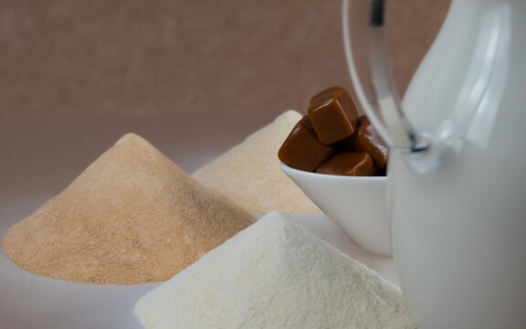 Drei Pulverhäufchen, Schüssel mit Karamellbonbons und weiße Milchkanne auf Tisch.