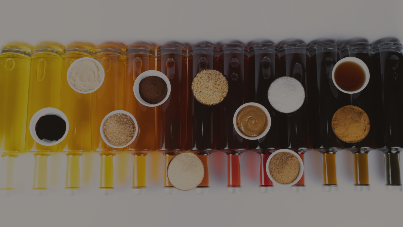 Reihe bunter Flaschen mit Flüssigkeiten, darüber Schälchen verschiedener Pulver, Gewürze und Soßen.