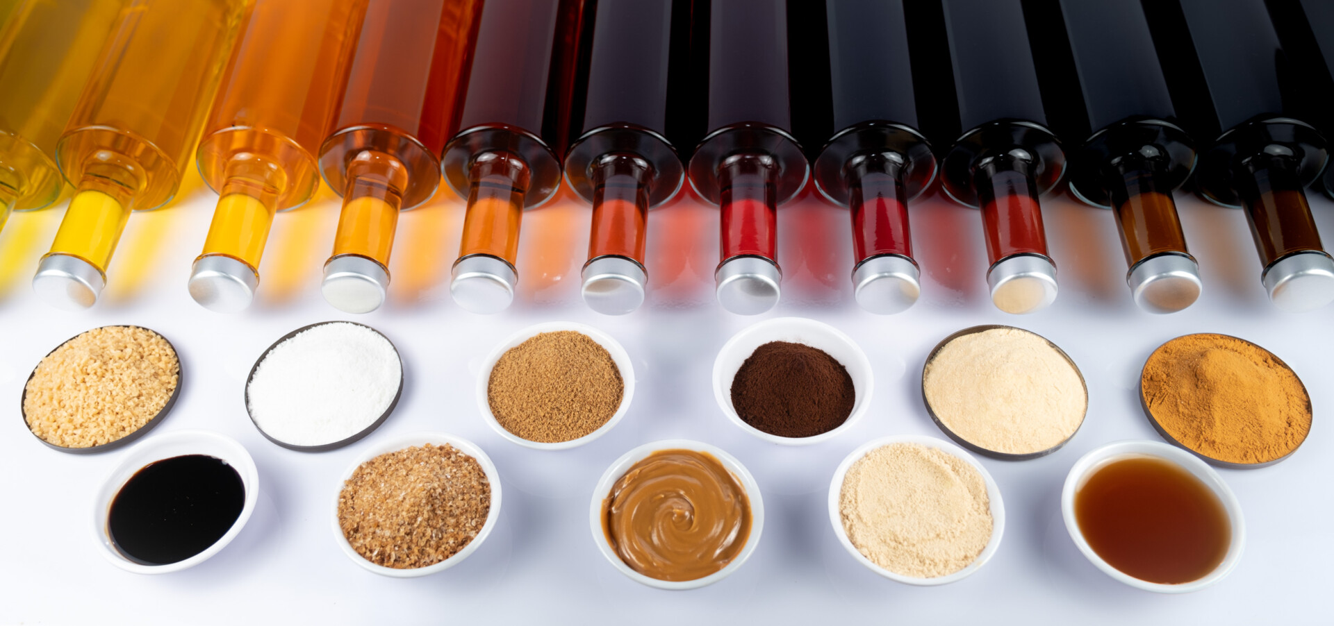 Reihe bunter Flaschen mit Flüssigkeiten über vielen Schälchen gemischter Pulver und Saucen.